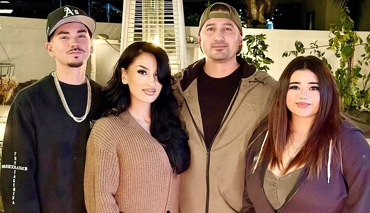 Four individuals stand together in front of a modern building, smiling and posing for the camera.